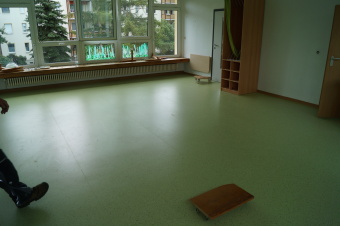 zu sehen ist ein leerer Raum mit breiter Fensterfront und grünem Fußboden