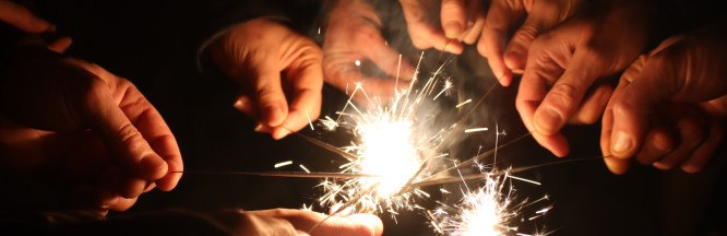 zu sehen sind Hände, die funkende Funkenstäbe in der Hand halten