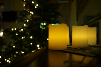 zu sehen sind leuchtende Kerzen in Nahaufnahme vor einem Weihnachtsbaum
