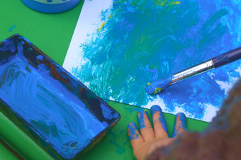 zu sehen ist ein Kind, das mit blauer Farbe malt