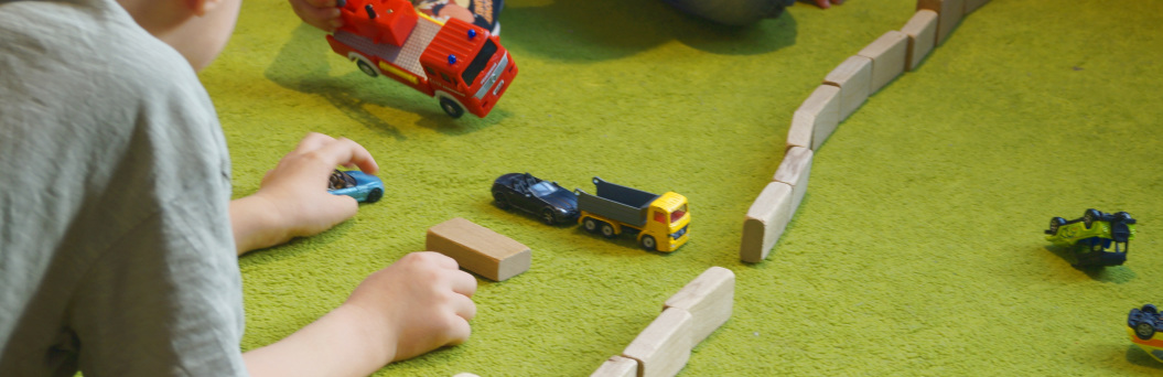 zu sehen ist ein kind, das mit Bausteinen und Autos spielt