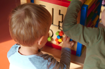 zu sehen sind zwei Kinder, die an einem  Spielewürfel spielen