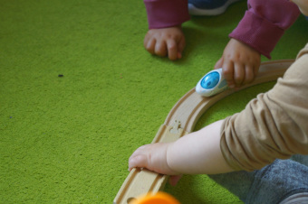 zu sehen sind zwei Kinder, die gemeinsam mit einem Zug spielen