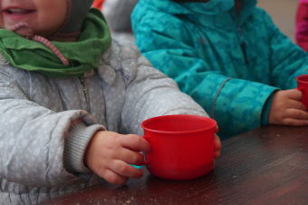 zu sehen sind 2 Kinder, die je eine rote Tasse ind er Hand halten