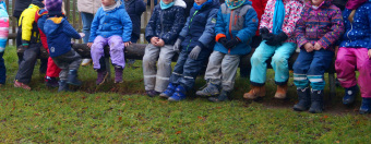 zu sehen sind viele Kinder, die beieinander sitzen