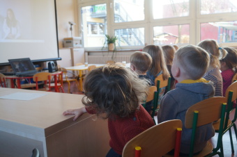 zu sehen sind Kinder bei einem digitalen Meeting, Sie schauen auf eine Leinwand