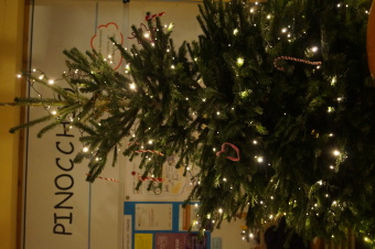 zu sehen ist ein beleuchteter Weihnachtsbaum. Im Hintergrund ist der Schriftzug "Pinocchio" zu lesen.