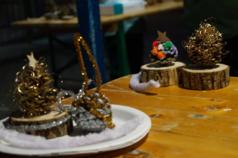zu sehen sind weihnachtlich gestaltete Kiefernzapfen mit Goldfäden und bunten Pompoms.