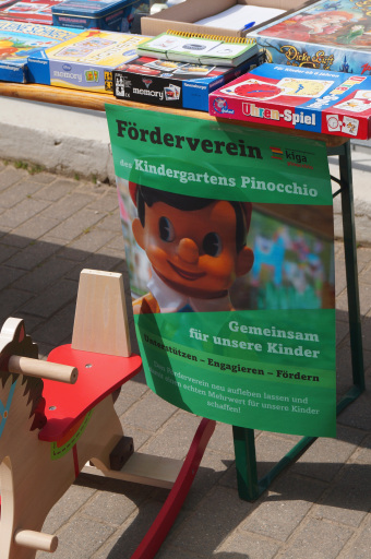 zu sehe ist ein Flyer des Fördvereins Kindergarten Pinocchio und ein Teil eines Flohmarktstandes mit Spielen