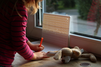 Ein Kind steht am Fenster und spielt.