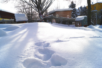 zu sehen ist der Garten des Kindergartens, mit Schnee bedeckt, darüber fliegen Seifenblasen