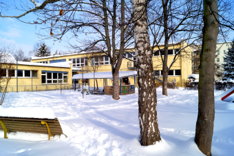 zu sehen ist das Gebäude der Kita und der Garten, vollständig mit Schnee bedeckt